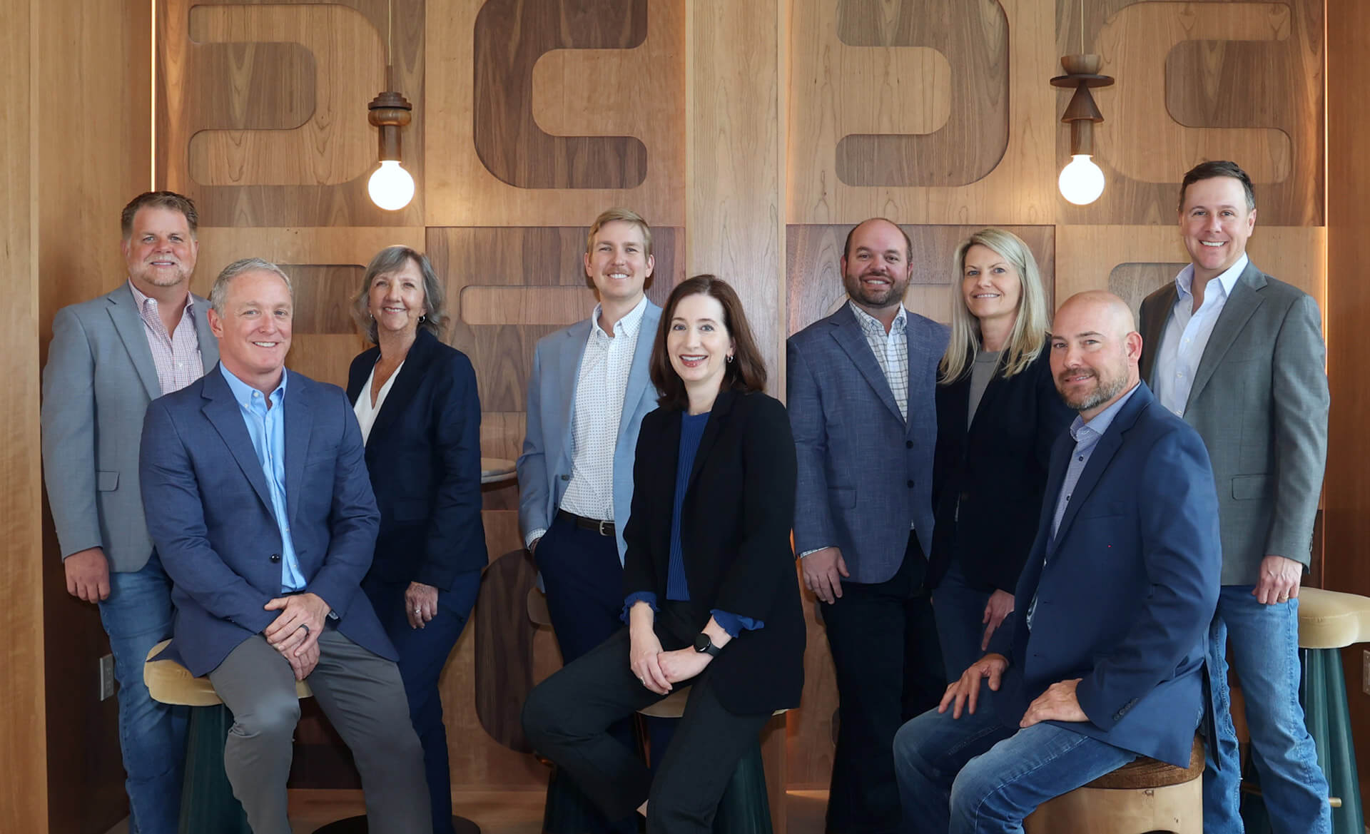 Pearlstone Partners team posed in the lobby of The Code Hotel in Austin, featuring warm wood interiors and arched architectural detailing.
